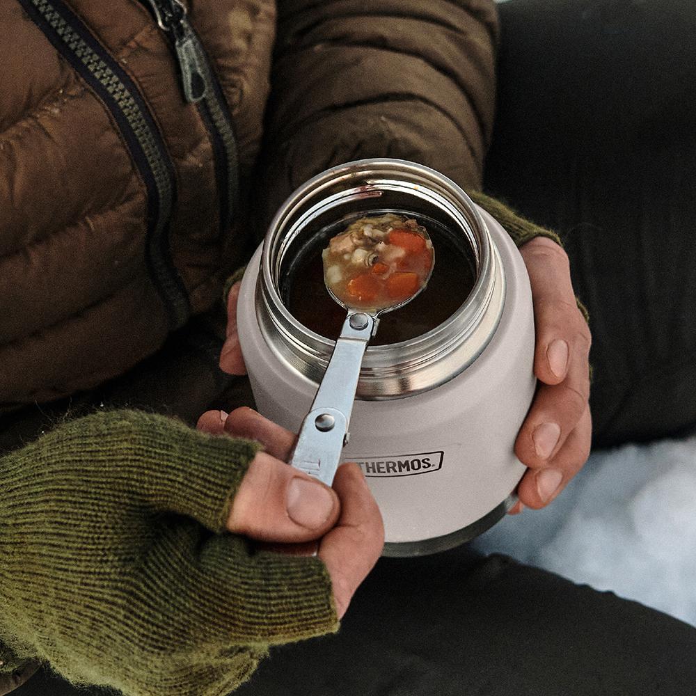 Man holding a Thermos 16oz Food Jar with soup on its stainless steel spoon.