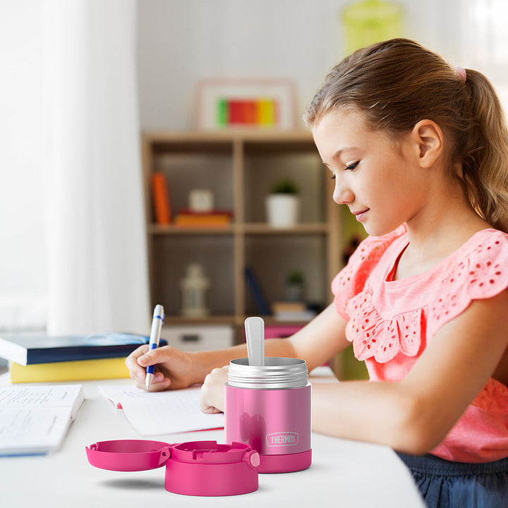 10 ounce Funtainer food jar open on a table next to a girl doing homework.
